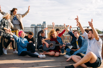 Carefree exchange students singing together on a rooftop their hands in the air. Bonding, friendship youth happiness