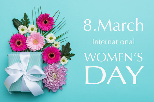 Happy Women's Day Pastel Candy Colors Background. Floral flat lay greeting card with beautifully wrapped present.