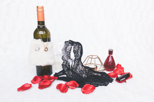 Valentines Day concept. Black g-strings with bottle of wine, roses and candles on white textured background. Isolated.