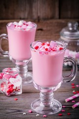 Pink hot milk with marshmallow and sugar hearts in a glass mug for Valentine Day