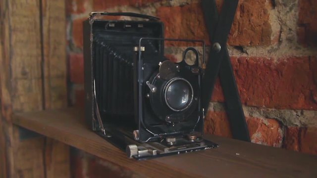 vintage retro camera on a wooden shelf against a brick wall background