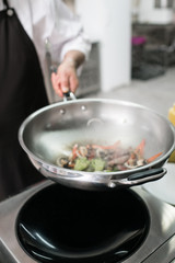 Chef showing off his professional skills. Cooking master at work in restaurant kitchen. Vegetables and meat mixing in the air technique