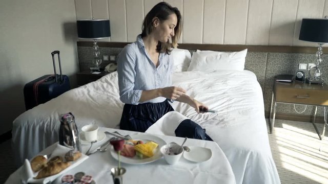 Happy businesswoman taking photo of food during breakfast in bed at hotel
