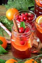 Punch with cranberries and orange decorated with mint and a stick of cinnamon in glass vessels