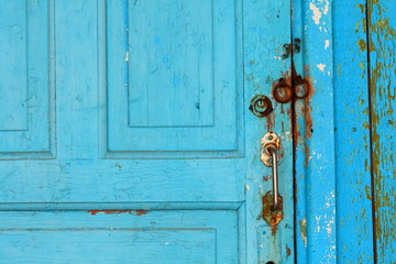 Fragment of closed old blue vintage wooden door with door handles and hinges for a padlock