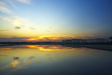 Fototapeta na wymiar White oil tank, water reflection, beautiful evening