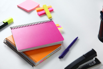 Colorful notebooks and office supplies on white table.
