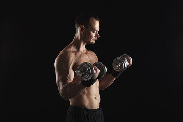 Strong athletic man with dumbbell showes naked muscular body