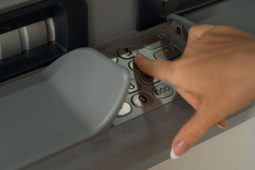 Fototapeta premium The girl dials the password in the ATM