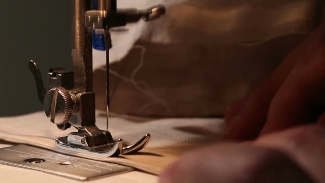 Male sewer working with fabric and thread on sewing machine