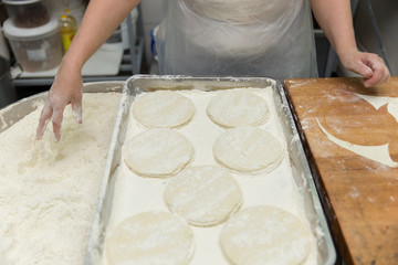 The cook prepares a round cutout from the dough