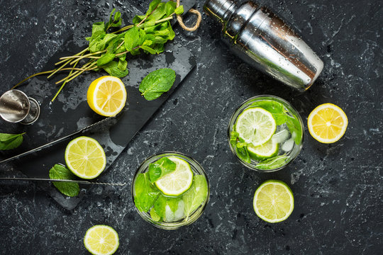 Mojito cocktail with lime and mint in highball glass on a stone table. Drink making tools and ingredients for cocktail.
