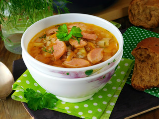 Soup with sausages in a white bowl on a green polka dots cloth