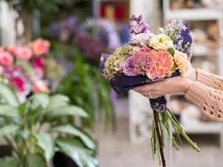 Timely flower bouquet delivery for on a special day - birthday or anniversary. Women hands holding a creative arrangement of roses peonies hydrangeas and lilacs