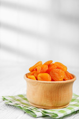 A useful dried apricot in a wooden bowl. The concept is healthy food, vegetarianism, diet, vitamins.