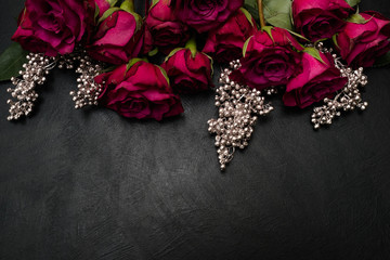 Fototapeta na wymiar Gothic wedding flowers decor. Dark red or burgundy roses with silver adornment on black background. Bold, daring ,alternative ,and luxury reception party flower arrangement