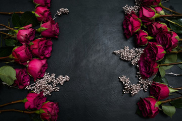 Gothic wedding flowers decor. Dark red or burgundy roses with silver adornment on black background....