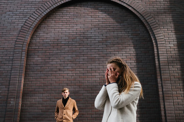 Young love and dating. Relationship problems. Separation breakup. Emotional girl crying covering her face. Brick wall copyspace background