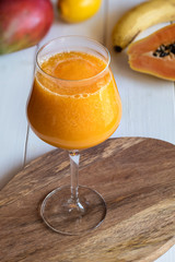 Fresh smoothie juice from a papaya fruit, banana, mango and lemon in glass.