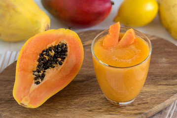 Fresh smoothie juice from a papaya fruit, banana, mango and lemon in glass.