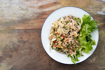 Top view of Thai food spicy minced pork salad on wood background