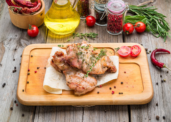 Grilled chicken breast on a wooden board with tomatoes and mushrooms