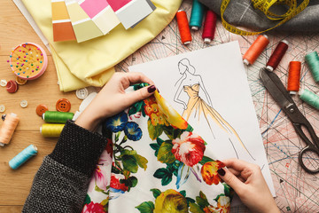 Female fashion designer working with fabric sample and drawn illustration
