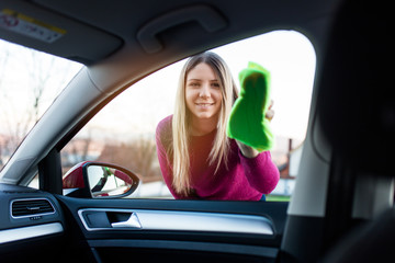 Young woman cleaning car with microfiber cloth, car detailing (or valeting) concept. 