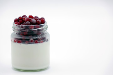 Fresh berries in the jar with the yogurt. On white background.