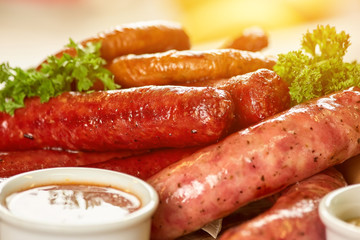 Different types of sausages closeup. Different types of juicy sausages and sauce in pot closeup.