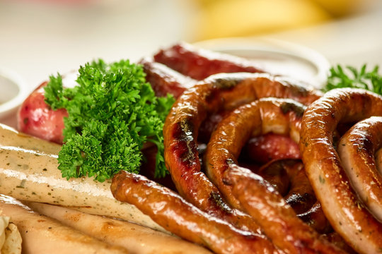 Curly and straight sausages with parsley. Closeup smoked sausages.