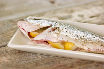 Lemons inside fish closeup. Gutted raw fish with lemons inside.