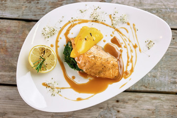 Served dish with salmon and garnish, down view. Salmon, soy caramel sauce, lemon, bell pepper and patty of parsley.