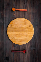 Make menu or write recipe. Mock up for menu or recipe. Wooden cutting board near spices and ingredients on dark wooden background top view