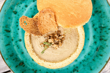 Mushroom cream soup with garnish, top view. Soup with mushrooms and toasts in bread pot, down view.
