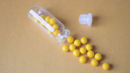 Ascorbic acid is scattered out of the jar on an orange background