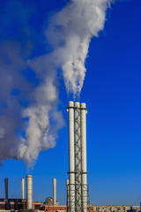 White smoke goes from a pipe on a background of blue cloudless sky