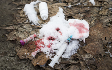 Obraz premium syringe with the drug, gauze with blood, the bulb on the snowy ground