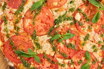 Close up sliced pizza with tomatoes, cheese and greens. Tomatoes pizza close up.