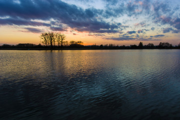 Sunset on the lake and reflection of clouds in the water