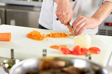 Obraz na płótnie Canvas Chef dicing carrot. Chief hands dicing carrot into small pieces.
