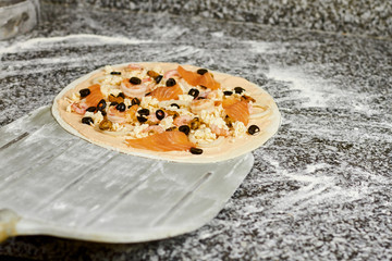 Metal pizza peel taking pizza from the table. Shovel taking uncooked pizza.