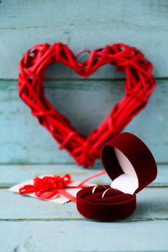 Background, texture on St. Valentine's day February 14: red heart, flowers and a red velvet box with two wedding rings on a blue wooden background, concept of love, wedding, engagement,