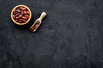 Roasted cocoa beans on black background top view copy space. Raw material for cocoa powder. African or Latin American product