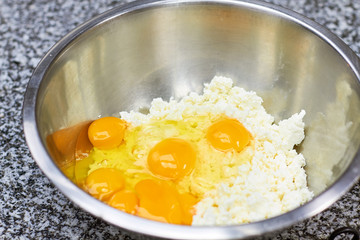 Egg yolks on chopped cheese, close up. Metal bowl with yolk and cheese close up.