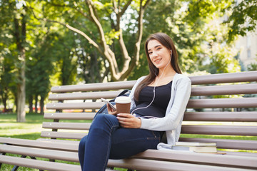 Obraz premium Student sitting in park and using smartphone