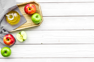 Apple cider vinegar in bottle among fresh apples on white wooden background top view copy space
