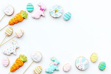 Sweets for celebrate Easter. Gingerbread in shape of easter bunny and easter eggs. White background top view copy space
