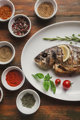 Whole grilled dorado with lemon slices on table