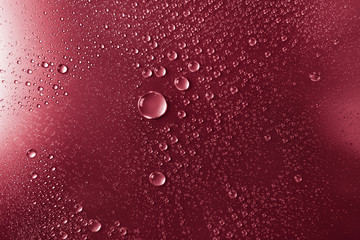 Bubbles of water on a shaded surface, red background